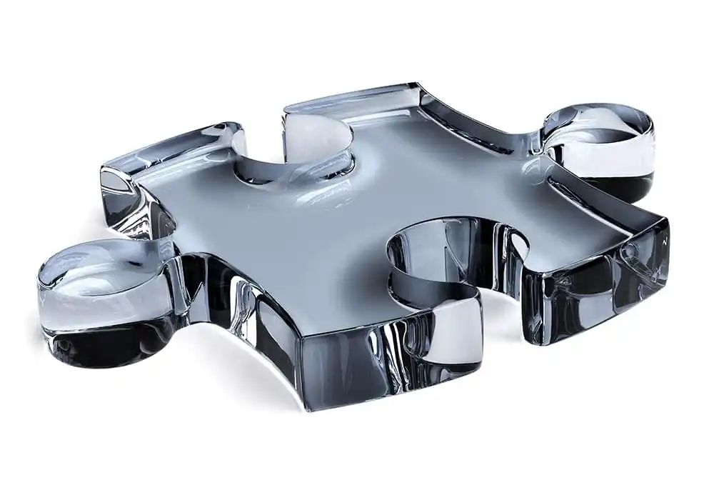 Nahaufnahme eines einzelnen Puzzleteils in transparenter Glasoptik vor hellem, weißem Hintergrund.