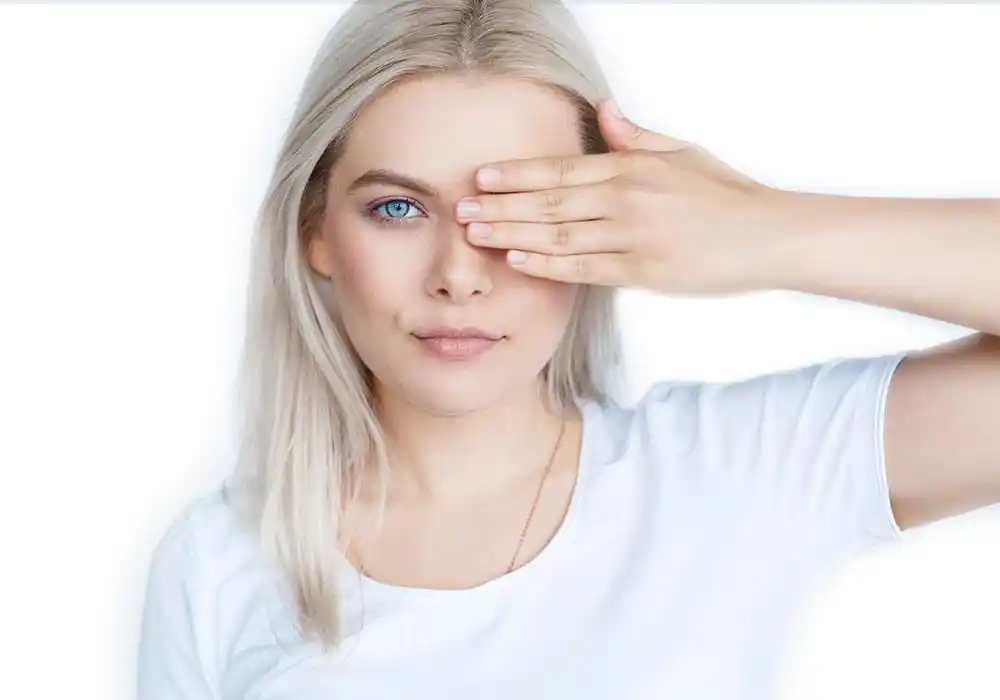 Porträt einer Frau, die ein Auge mit der Hand zuhält und den Blick direkt auf die Kamera richtet.