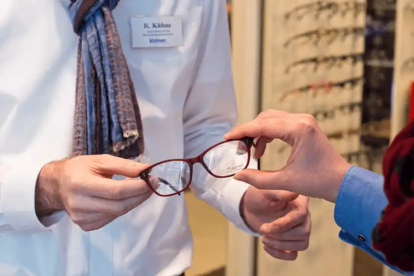Kundin im Optikgeschäft schaut sich eine Brille während einer persönlichen Beratung genau an