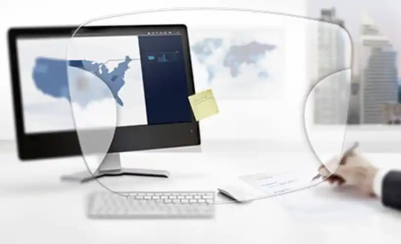 Brillenglas-Linse vor einem geöffneten Laptop, dargestellt in einem Bürosetting