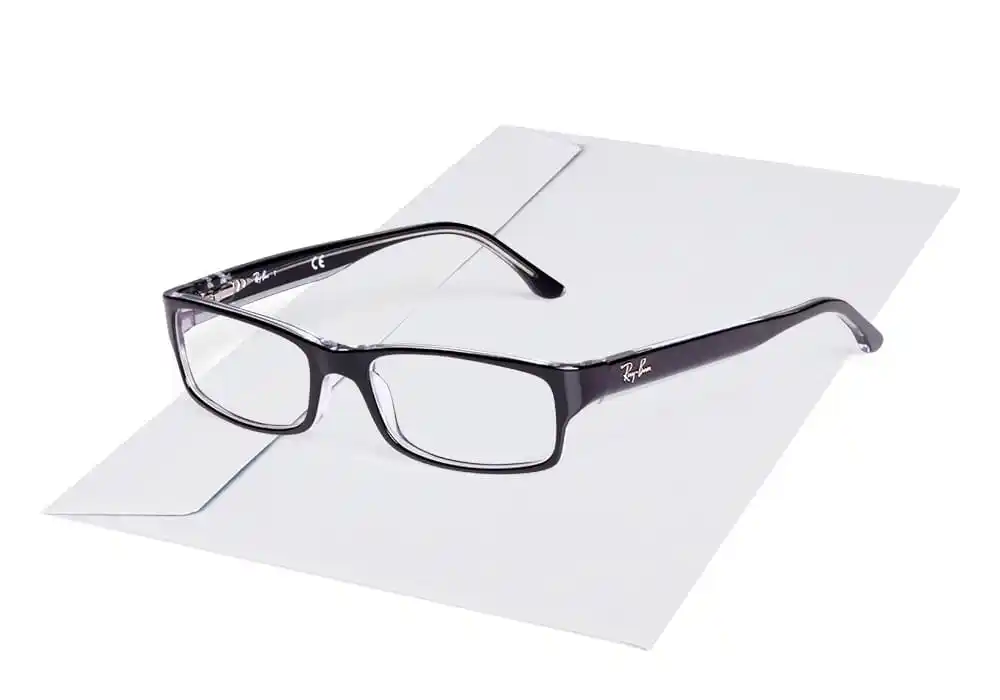 Brille liegt auf einem geschlossenen Kuvert in einer klaren, minimalen Studioaufnahme